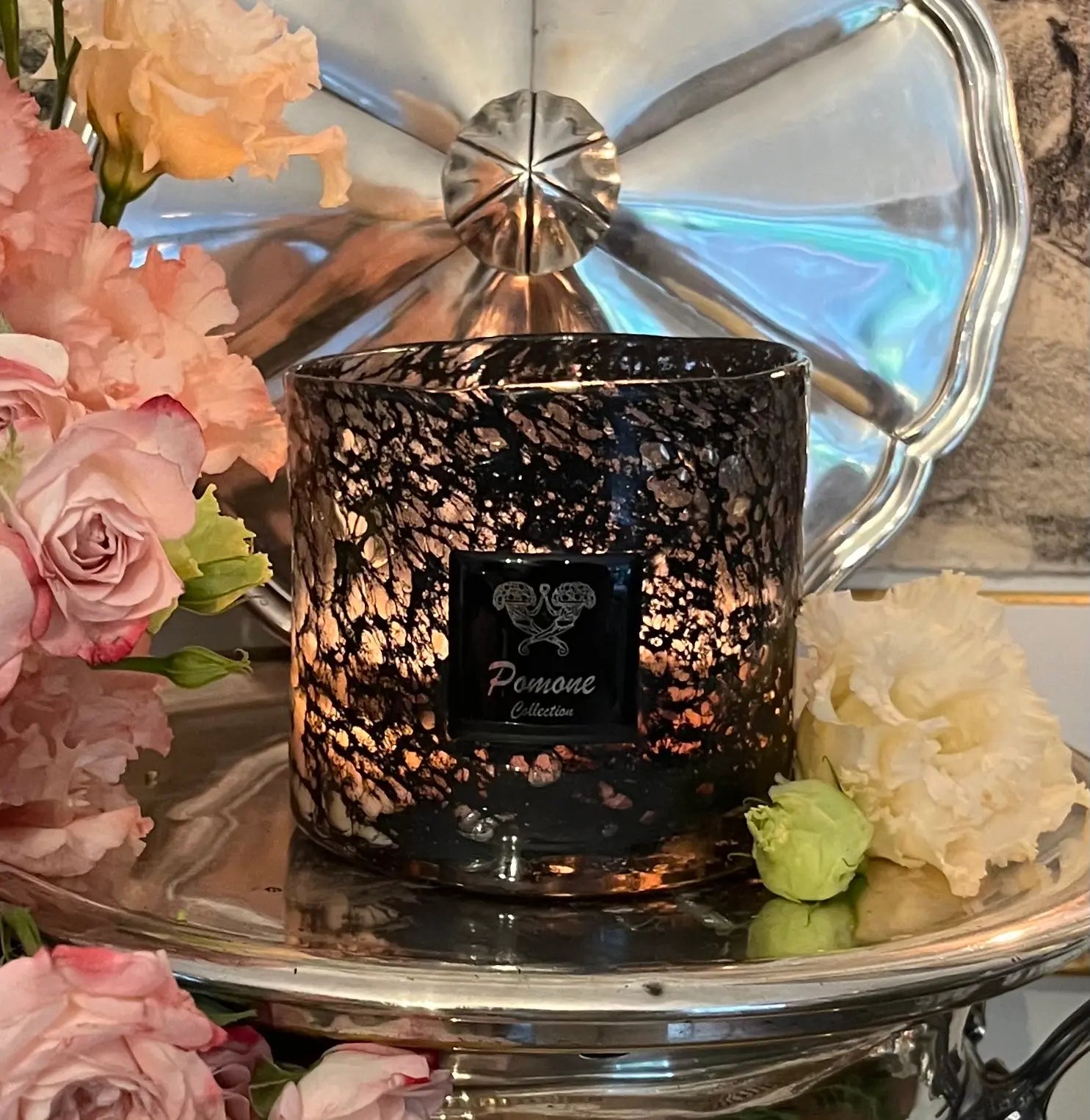 Bougie noire et transparente, vue de face avec des fleurs roses et blanches