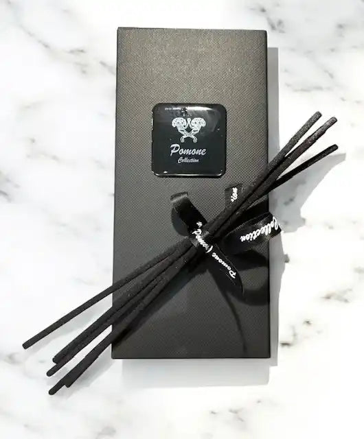 Emballage de diffuseur noir avec battons diffuseurs, vue de face sur marbre blanc