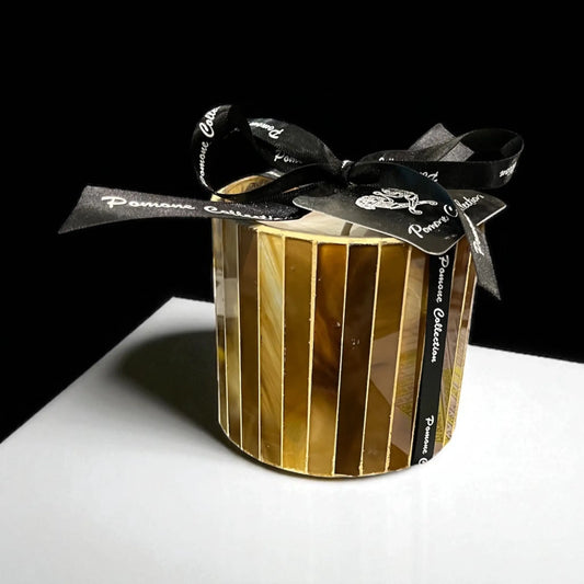 Bougie couleur cognac, ambre, vue de face sur meuble blanc et fond noir

