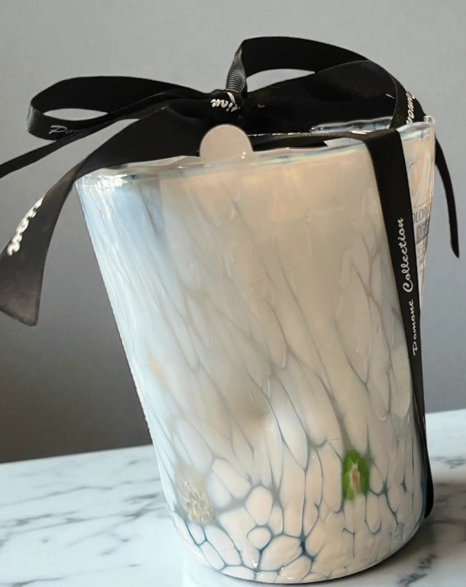 Bougie blanche avec des traces vertes et bleues, vue de côté sur marbre blanc
