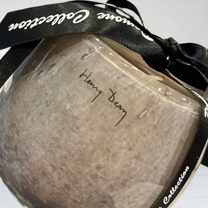 Bougie arrondie couleur parme gris, vue de derrière avec ruban et signature sur fond blanc 