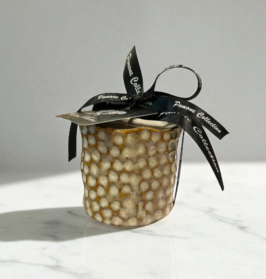 Bougie en céramique beige et blanc cassé, vue de face sur marbre beige
