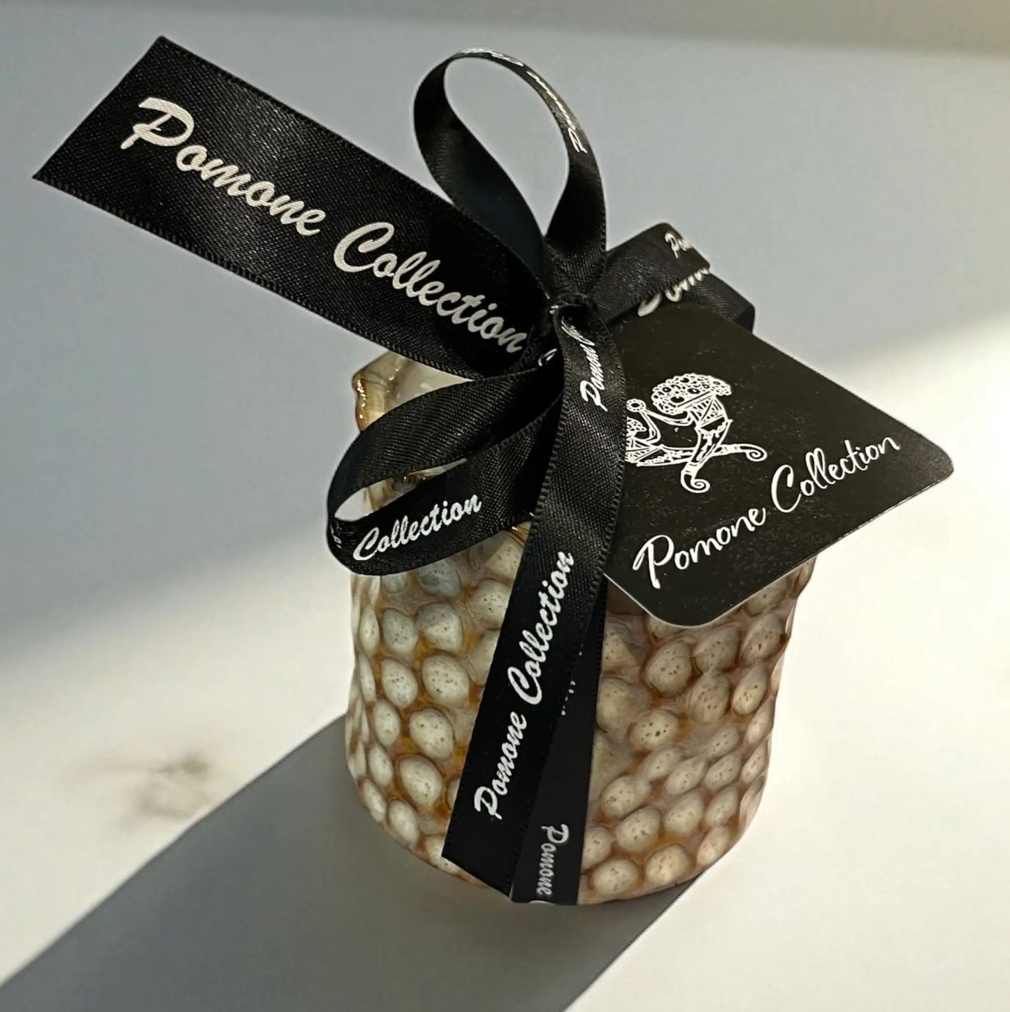 Bougie en céramique beige et blanc cassé avec ruban et étiquette