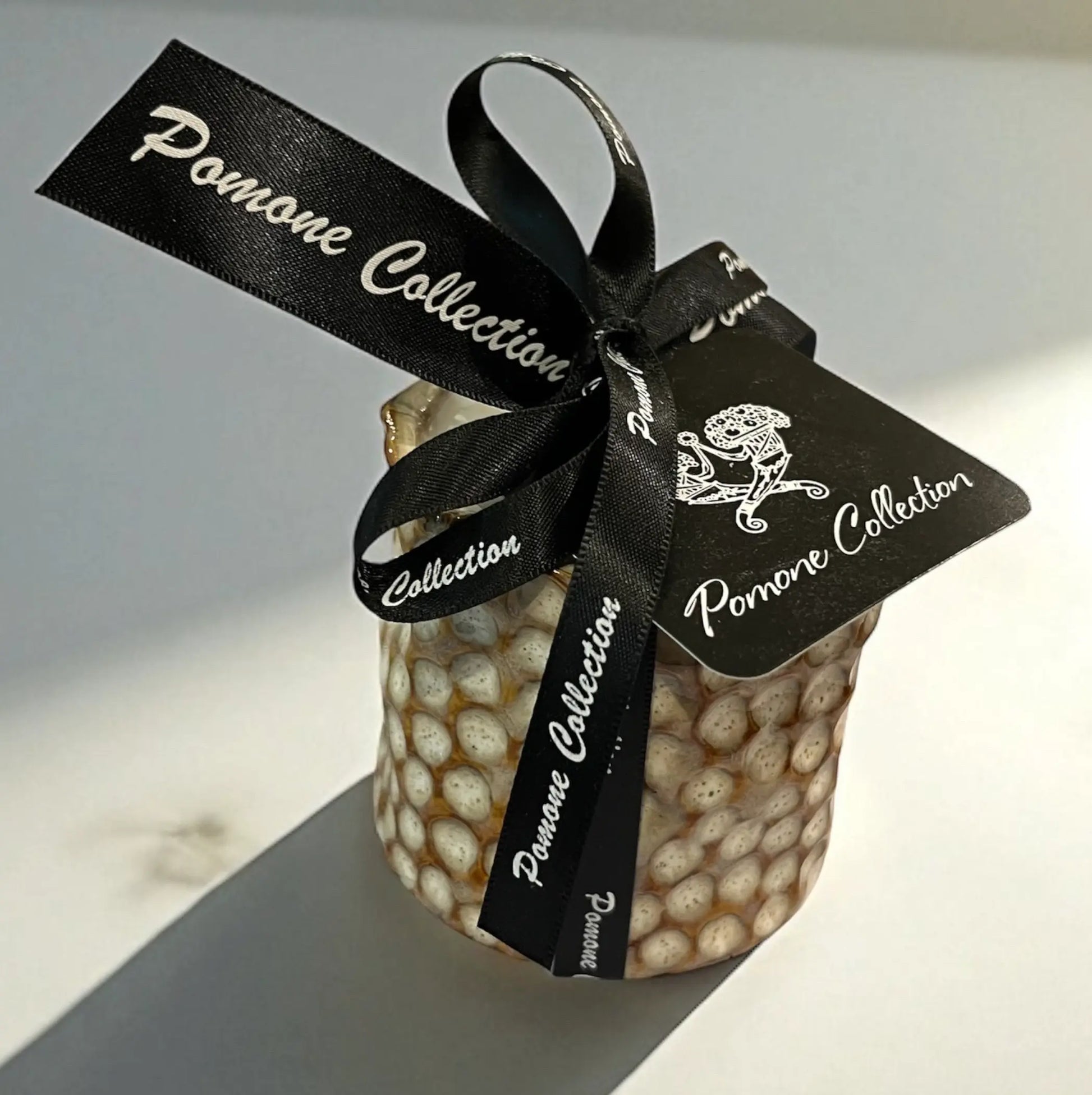 Bougie en céramique beige et blanc cassé avec ruban et étiquette