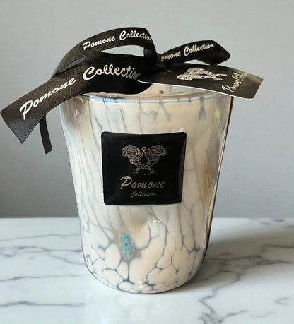 Bougie blanche avec des traces bleues et vertes, vue de face sur marbre blanc