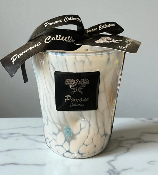 Bougie blanche avec des traces bleues et vertes, vue de face sur marbre blanc