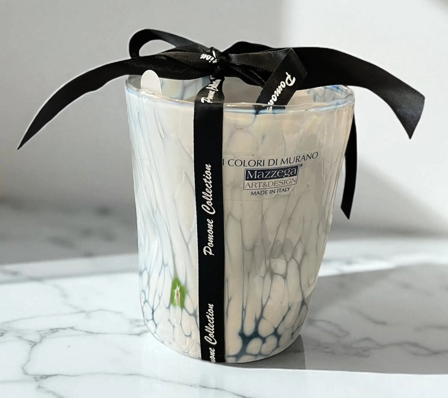 Bougie blanche avec des traces bleues et vertes, vue de derrière avec signature sur marbre blanc
