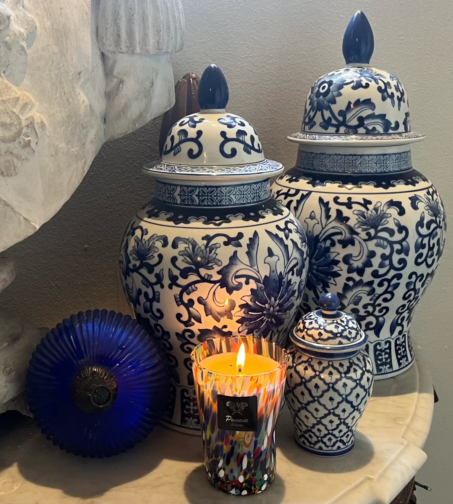 Bougie multicolore allumée sur marbre blanc avec vases derrière